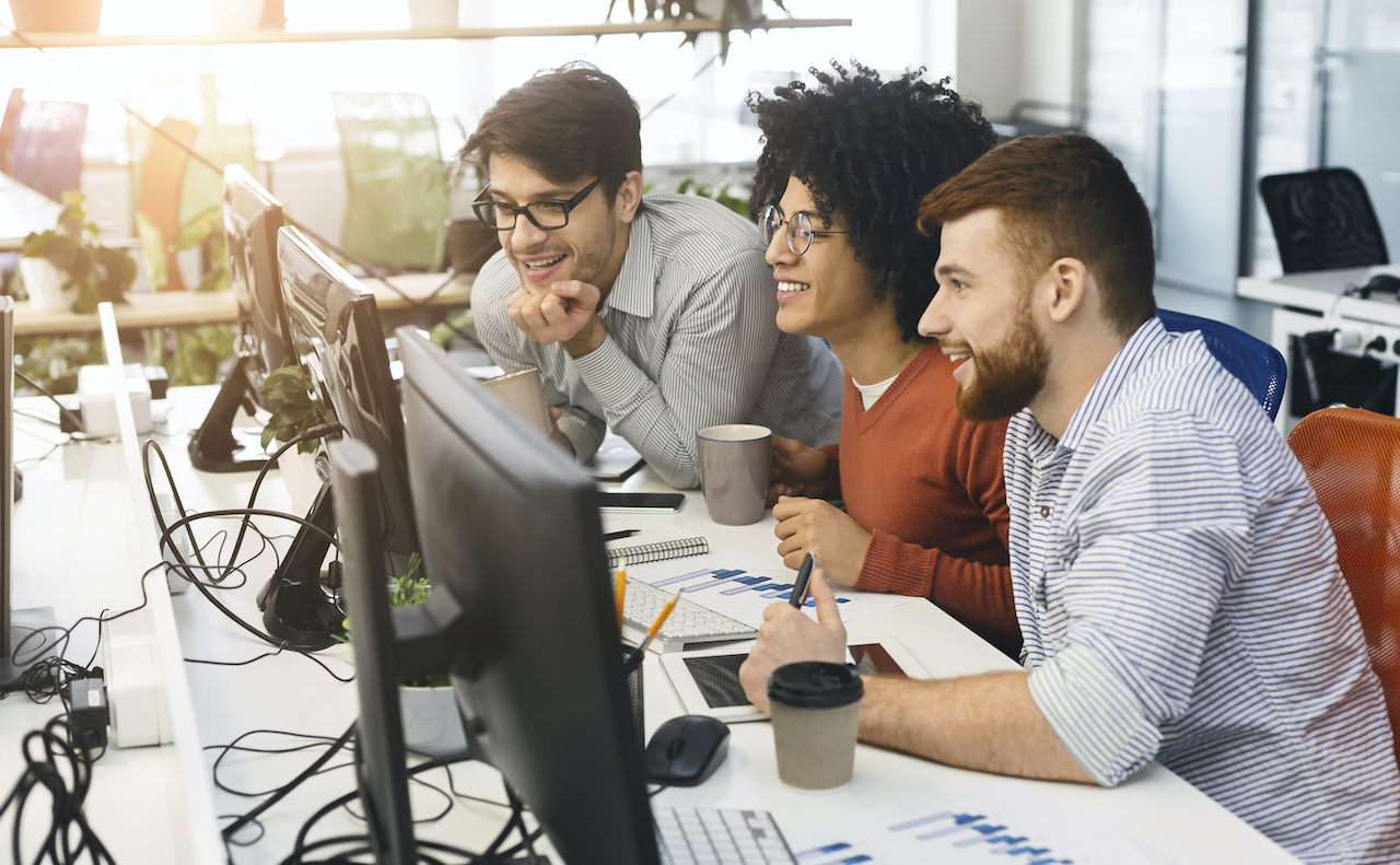 three members of a managed service provider team smile around a computer